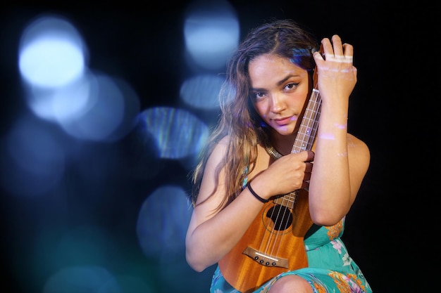 Porträt einer Frau, die die Ukulele spielt, isolieren auf schwarzem Hintergrund. Frei von Kopienraum