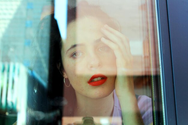 Foto porträt einer frau, die durch das fenster schaut