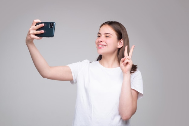 Porträt einer Frau, die ein Mobiltelefon verwendet Mädchen, das Smartphone über grauem Hintergrund hält