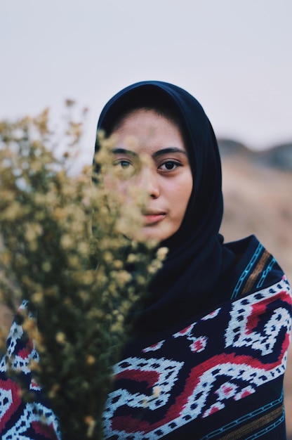 Foto porträt einer frau, die einen hijab mit blumen gegen einen klaren himmel trägt