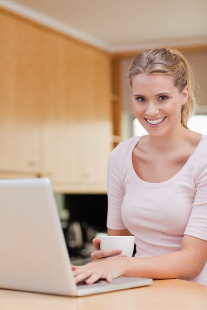 Porträt einer Frau, die einen Laptop beim Trinken des Kaffees verwendet