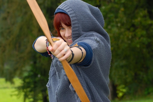 Foto porträt einer frau, die einen pfeil zielt, während sie an land steht