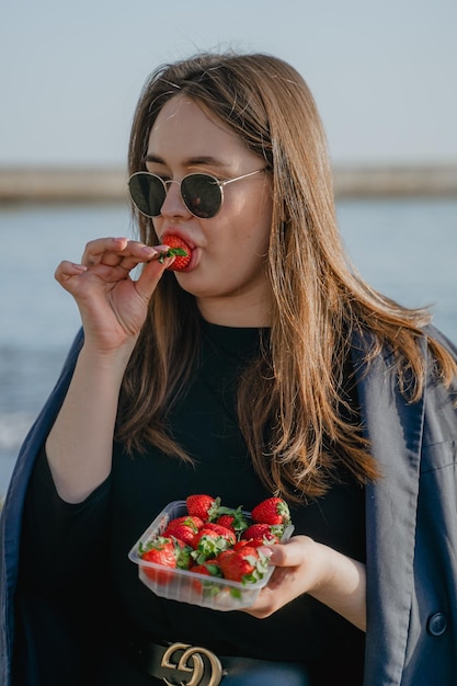 Porträt einer Frau, die Erdbeeren isst