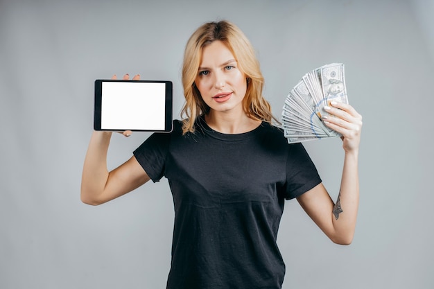 Porträt einer Frau, die Geld hält und leeren Tablet-Computerbildschirm zeigt