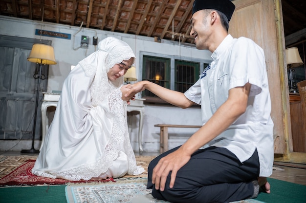 Porträt einer Frau, die ihrem Mann die Hand küsst, nachdem sie zu Hause zusammen gebetet hat