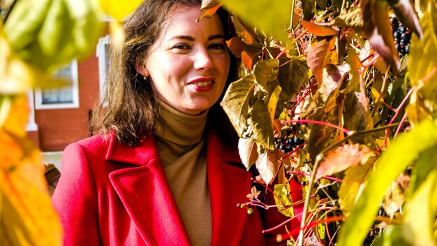 Foto porträt einer frau, die im herbst bei einer pflanze im garten steht