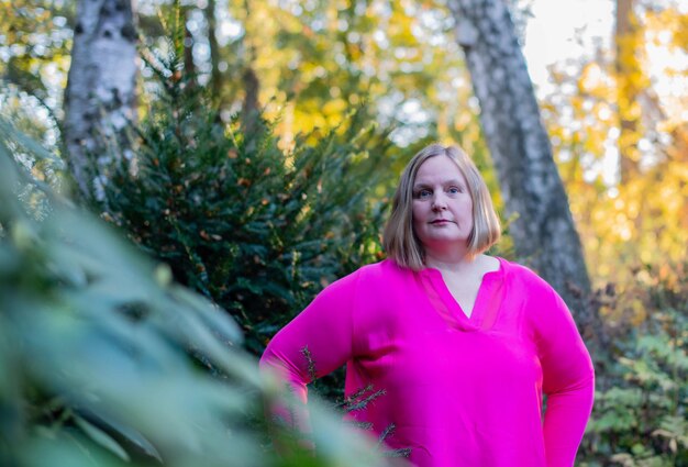 Porträt einer Frau, die im Park gegen einen Baum steht