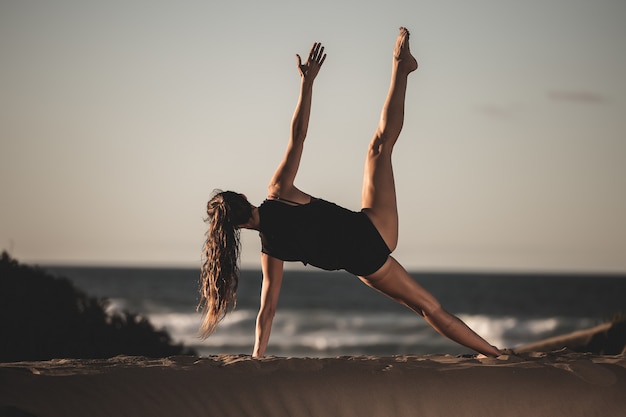 Porträt einer Frau, die Yoga am Strand tut