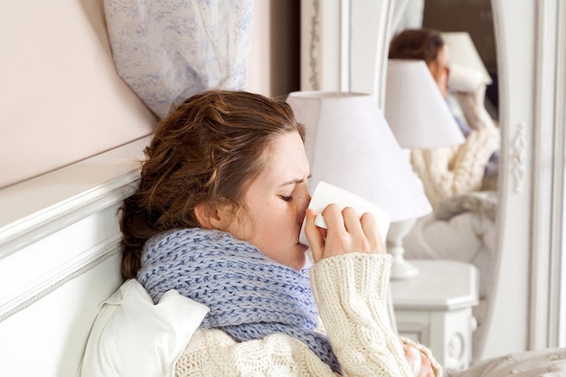 Foto porträt einer frau, die zu hause auf dem bett sitzt