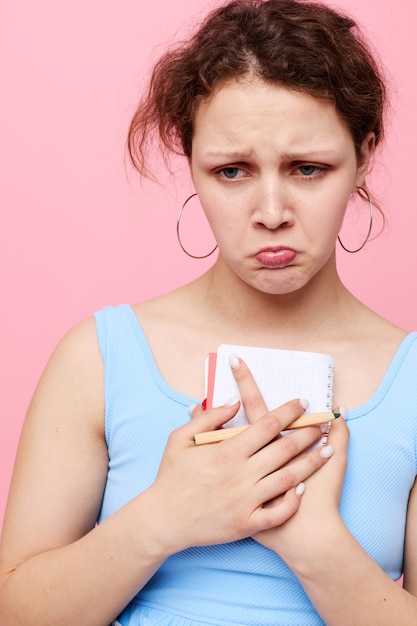 Porträt einer Frau in einem blauen T-Shirt mit einem roten Notizblock und einem Stift der unveränderten Nahaufnahme der Gefühle