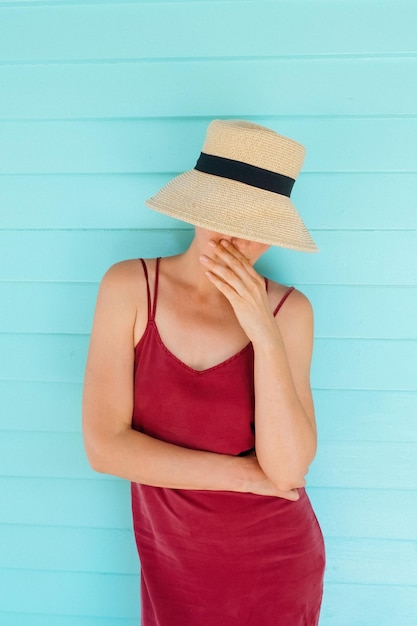 Foto porträt einer frau in einem stroh-sommerhut auf einem farbenfrohen aqua-hintergrund