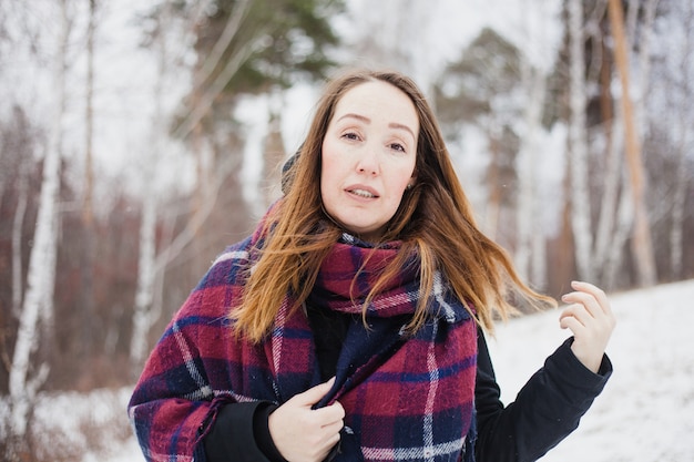 Porträt einer Frau in einem Winterwald, warme Kleidung, Schal