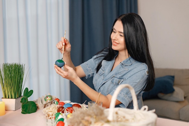 Porträt einer Frau in einer modernen leichten Küche und beim Bemalen von Ostereiern