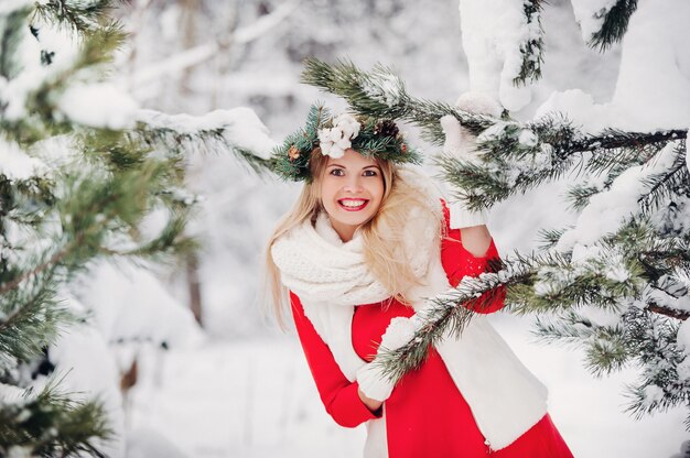 Porträt einer Frau in einer roten Jacke in einem kalten Winterwald. Mädchen mit einem Kranz auf dem Kopf in einem verschneiten Winterwald.