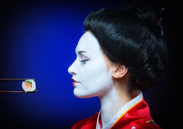 Porträt einer Frau in Geisha-Make-up, die Sushi isst