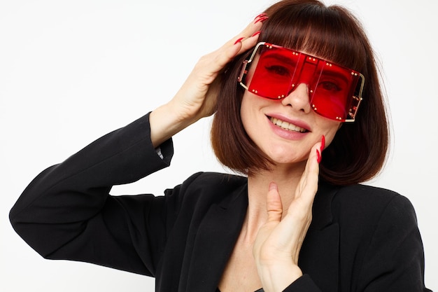 Porträt einer Frau in Rot mit stylischer Brille, Lederanzug, schwarze Jacke, isolierter Hintergrund