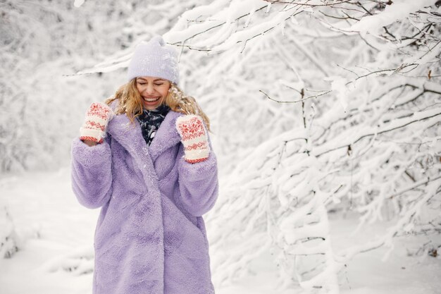 Porträt einer Frau in Strickmütze und lila Pelzmantel im Winter