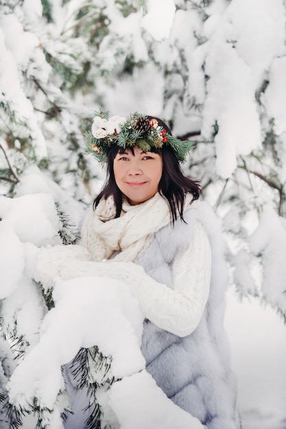 Porträt einer Frau in weißer Kleidung in einem kalten Winterwald. Mädchen mit einem Kranz auf dem Kopf in einem verschneiten Winterwald