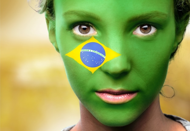 Foto porträt einer frau mit der flagge brasiliens im gesicht