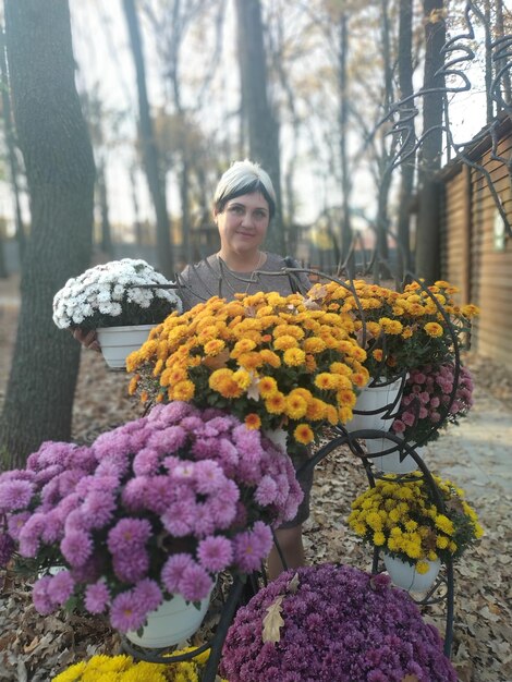 Foto porträt einer frau mit einem blumenstrauß gegen pflanzen