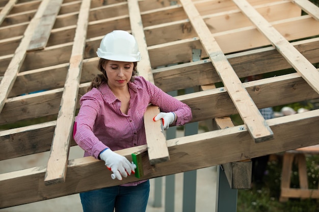 Porträt einer Frau mit Hut, die auf einer Baustelle auf Holz steht