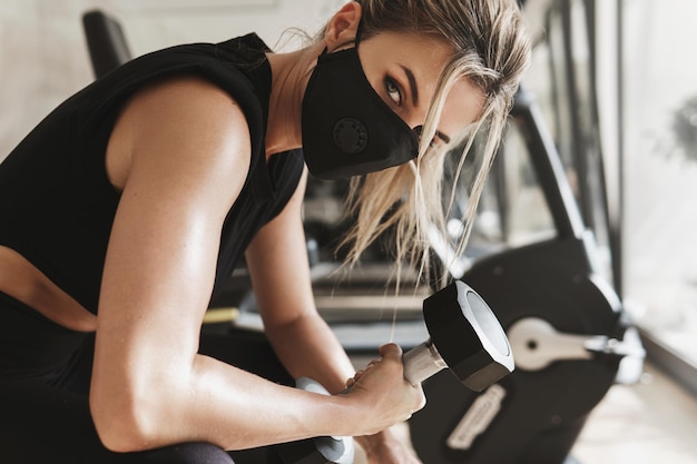 Porträt einer Frau mit Maske, die im Fitnessstudio trainiert
