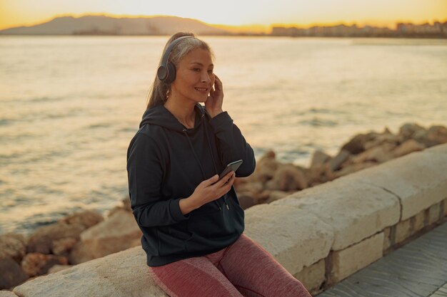 Porträt einer Frau mit schwarzem Hoodie, die sich nach dem Training am Meer ausruht