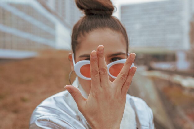 Foto porträt einer frau mit sonnenbrille, die gegen gebäude gestimmt