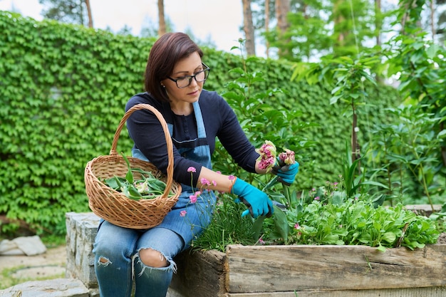 Porträt einer Frau mittleren Alters, die sich im Hinterhofgarten um ein Blumenbeet kümmert