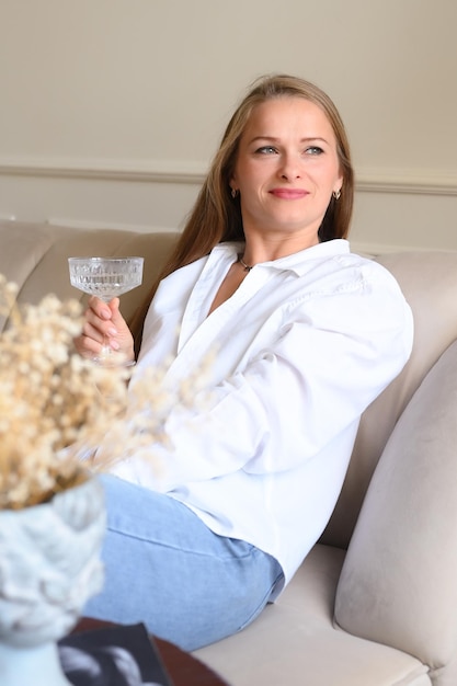 Porträt einer Frau mittleren Alters mit langen Haaren, die sich zu Hause entspannt Entspannen bei einem Glas Wein Vertikales Foto