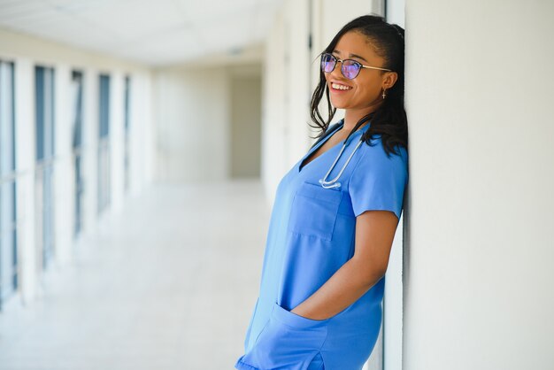 Porträt einer freundlichen, lächelnden, selbstbewussten medizinischen Fachkraft mit Laborkittel, verschränkten Armen mit Brille. Isolierte Krankenhaus Klinik Hintergrund.