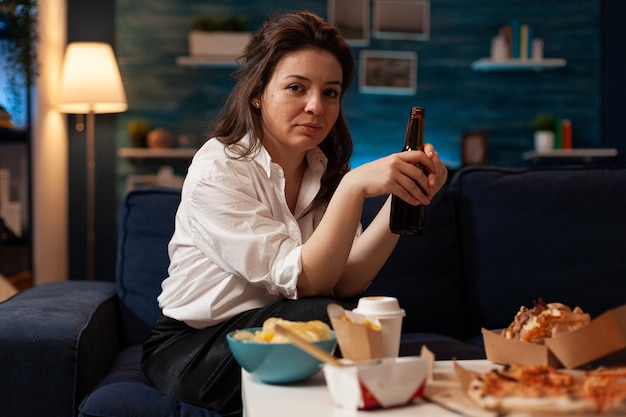 Porträt einer fröhlichen Frau, die auf der Couch sitzt und in die Kamera lächelt, während sie nach Hause geliefert wird