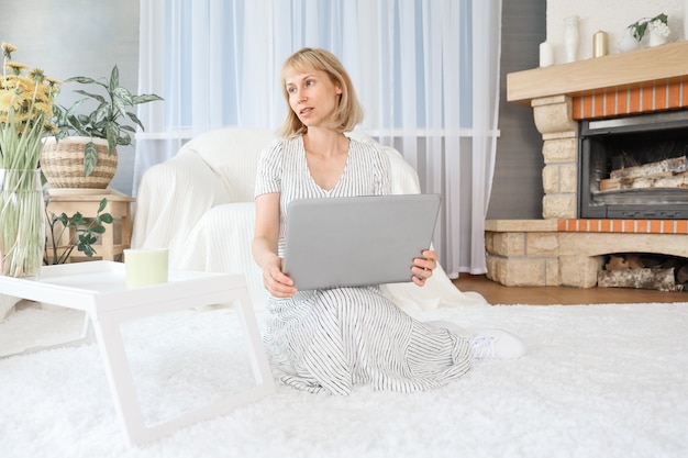 Porträt einer fröhlichen Frau zu Hause mit einem Laptop, die online mit einem Treffen mit Freunden verbunden ist.
