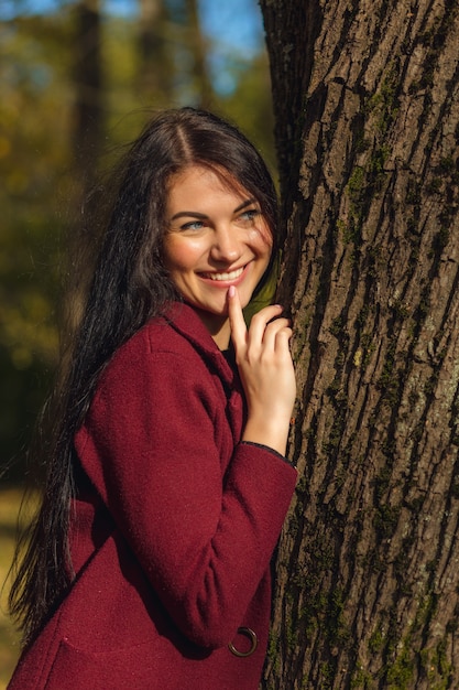 Porträt einer fröhlichen jungen Frau, die im Herbstpark genießt.