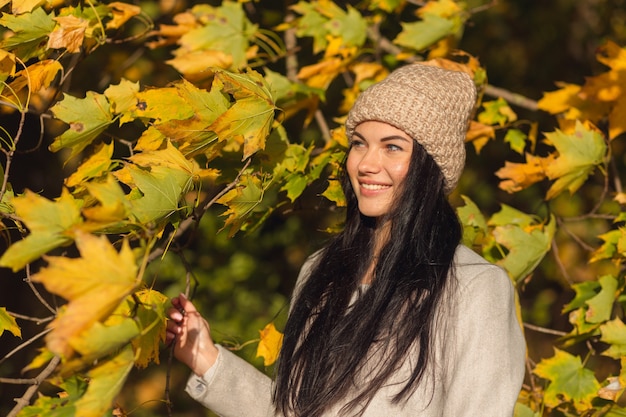 Porträt einer fröhlichen jungen Frau, die im Herbstpark genießt.