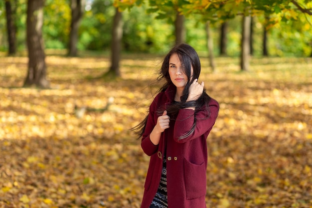 Porträt einer fröhlichen jungen Frau, die im Herbstpark genießt.