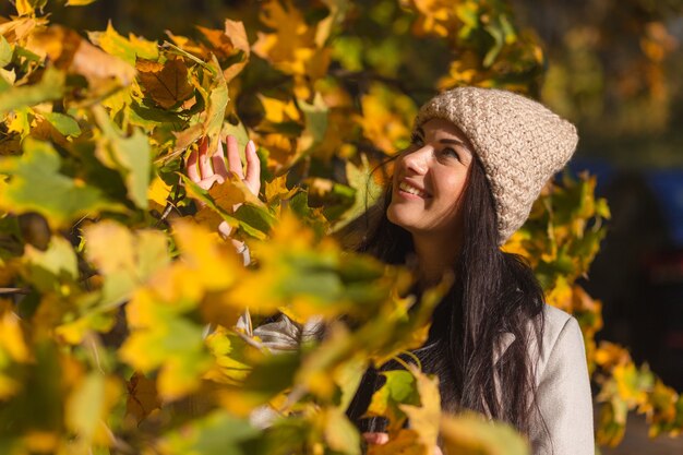 Porträt einer fröhlichen jungen Frau, die im Herbstpark genießt.