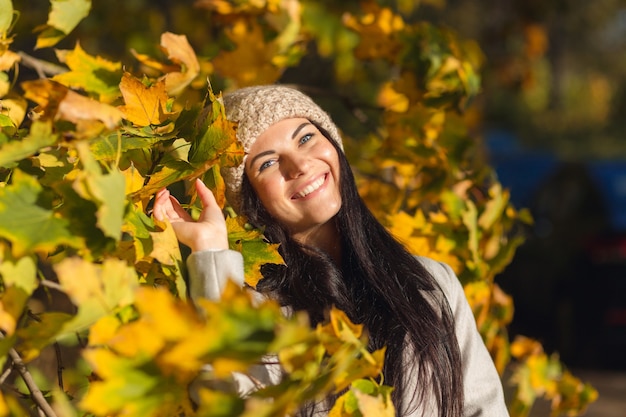 Porträt einer fröhlichen jungen Frau, die im Herbstpark genießt.