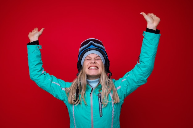 Porträt einer fröhlichen jungen Frau in einer Jacke, einem Helm und einer Skibrille