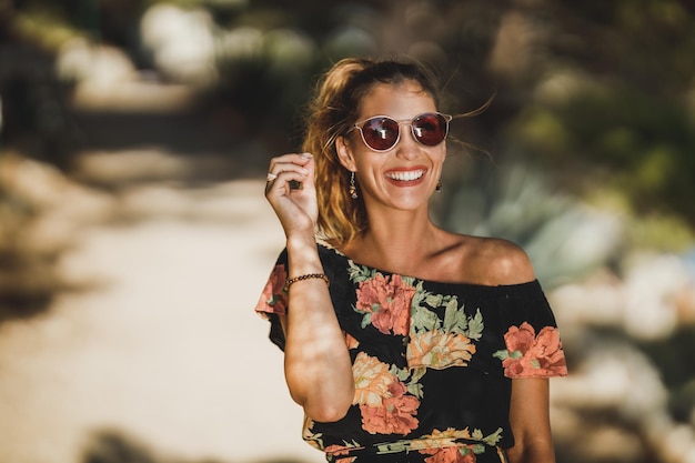 Foto porträt einer fröhlichen jungen frau mit sonnenbrille beim spaziergang durch einen pinienwald in der nähe des meeres. und genießt die sommerferien.