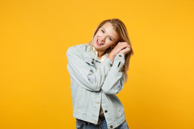 Porträt einer fröhlichen, lustigen jungen Frau in Denim-Freizeitkleidung, die in die Kamera blickt und die Hände in der Nähe des Gesichts hält, isoliert auf gelb-orangefarbener Hintergrundwand im Studio. People-Lifestyle-Konzept. Mock-up-Kopienbereich.