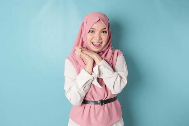 Porträt einer fröhlichen muslimischen Asiatin, die isoliert auf blauem Hintergrund in die Kamera lächelt