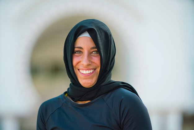 Foto porträt einer fröhlichen muslimischen frau, die einen hijab trägt, isoliert mit moscheehintergrund. horizontale ansicht der arabischen frau im freien. muslimische frauen, religion und gleichstellungskonzept.
