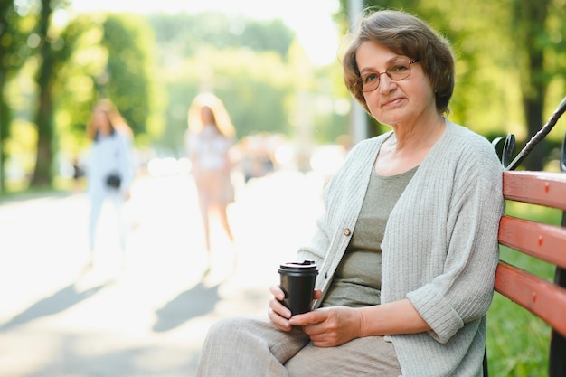 Porträt einer gealterten, positiven, friedlichen Dame, die auf einer Kaffeebank sitzt