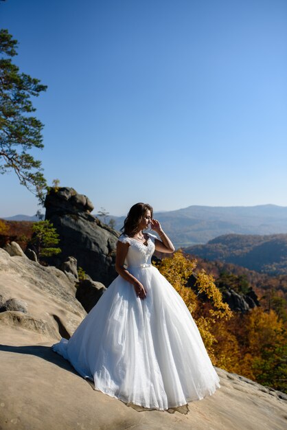 Porträt einer gebräunten Braut auf einem Hintergrund der Berge. Fotoshooting nach der Hochzeit auf Reisen in Erbsen ...