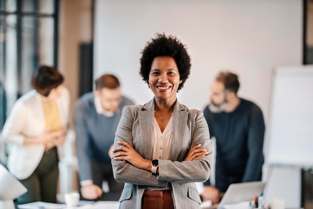 Porträt einer gemischtrassigen Führungskraft, die im Büro steht, während Geschäftsleute arbeiten