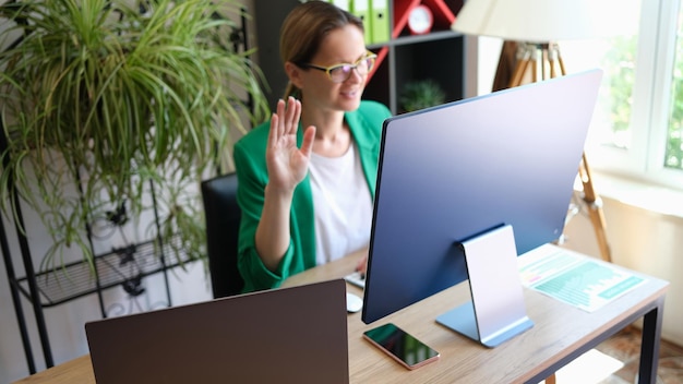 Porträt einer Geschäftsfrau, die eine Online-Videokonferenz abhält und online mit der Hand hallo winkt