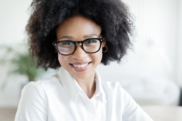 Porträt einer Geschäftsfrau in einem Büro mit lächelnder Brille, die Zähne zeigt