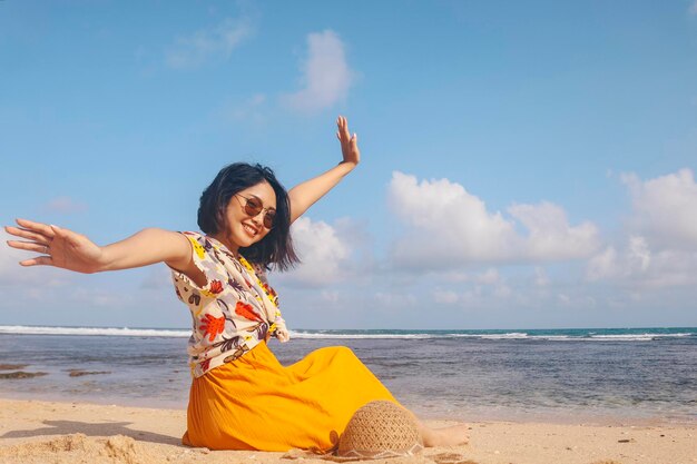 Porträt einer glücklich lächelnden asiatischen Frau am Strand mit Hut