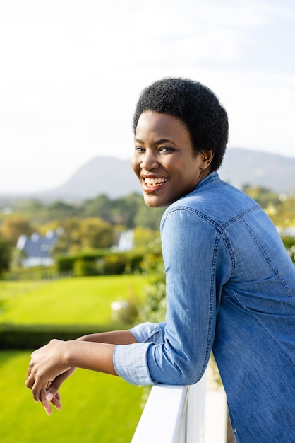 Porträt einer glücklichen afroamerikanischen Frau, die auf einer sonnigen Terrasse wohnt. Lebensstil, Natur und häusliches Leben, unverändert.